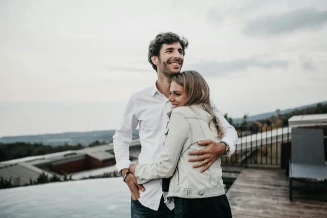 A couple on a rooftop terrace, laughing, held in each other's arms